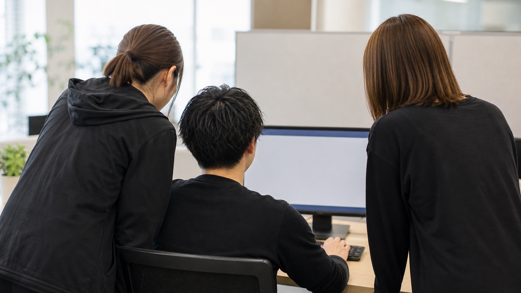 社内で画面を確認しながら仕事を進めるスタッフの後ろ姿